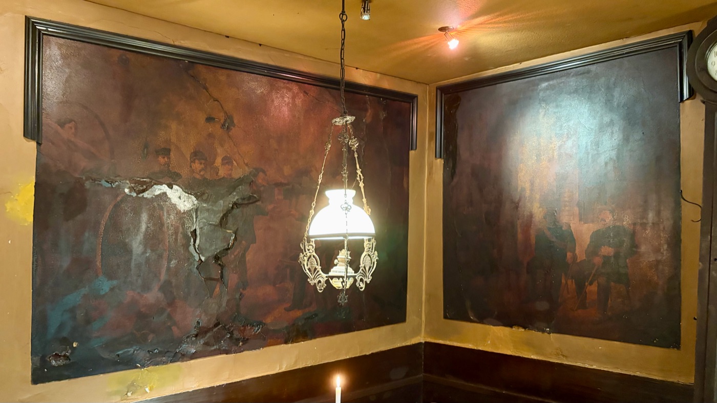 Alte, nachgedunkelte Wandgemälde aus den 1870er Jahren in der Gaststube, davor eine Messinglampe
